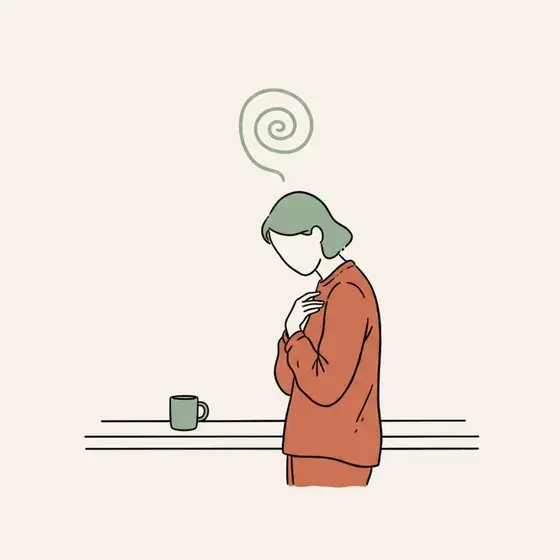 Person at a kitchen counter holding a mug, small spiral above their head